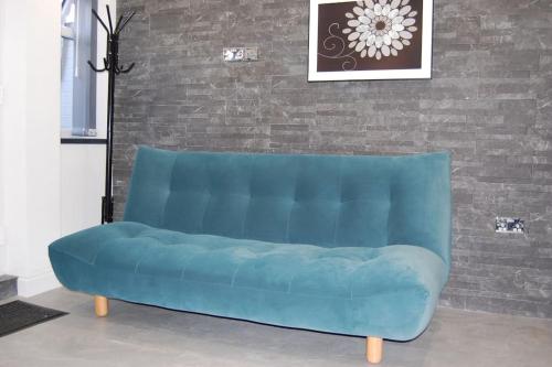 a blue couch in a room with a brick wall at Self contained studio apartment in Burley, Leeds in Headingley