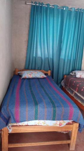 Bett in einem Zimmer mit einem blauen Vorhang in der Unterkunft Los Tunales 