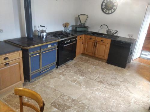 a kitchen with a black stove and a blue island at Mas du Roy in Sénéchas