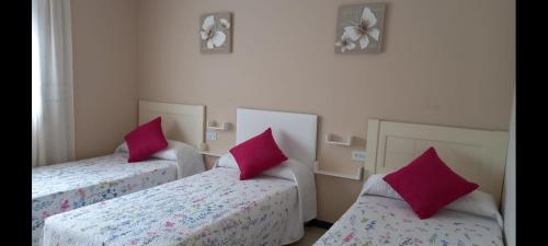 Duas camas com almofadas cor-de-rosa num quarto em Albergue Agarimo em Caldas de Reis