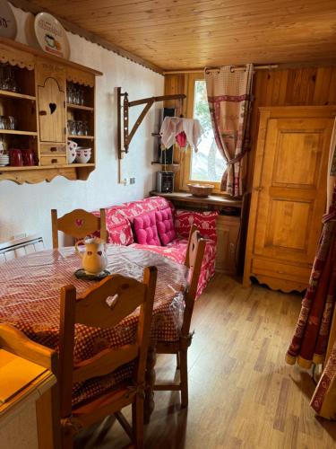 - un salon avec une table et un canapé rose dans l'établissement Appartement cosy a Montchavin, à La Plagne Tarentaise