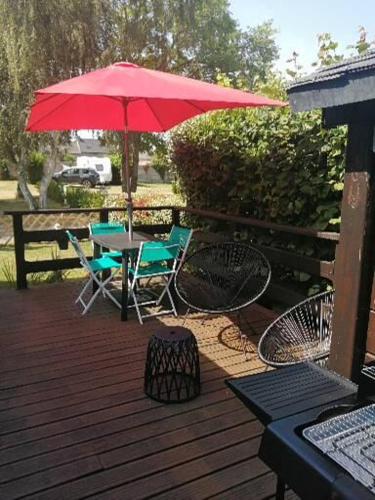 patio con tavolo, sedie e ombrellone rosso di Mobil home centre ville a Pleurtuit