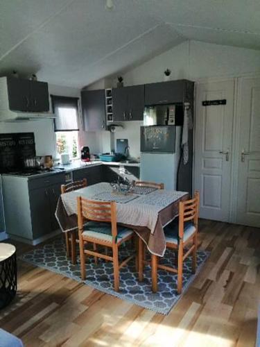 a kitchen with a table with chairs and a refrigerator at Mobil home centre ville in Pleurtuit