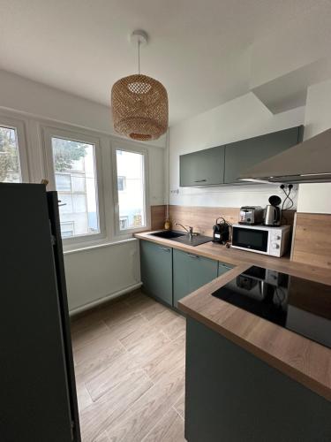 une cuisine avec des placards verts et un comptoir dans l'établissement Bel appartement - LM la Mer, à Berck-sur-Mer
