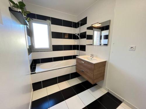 La salle de bains en noir et blanc est pourvue d'un lavabo et d'une baignoire. dans l'établissement Jolie maison de Ville au Mans, au Mans