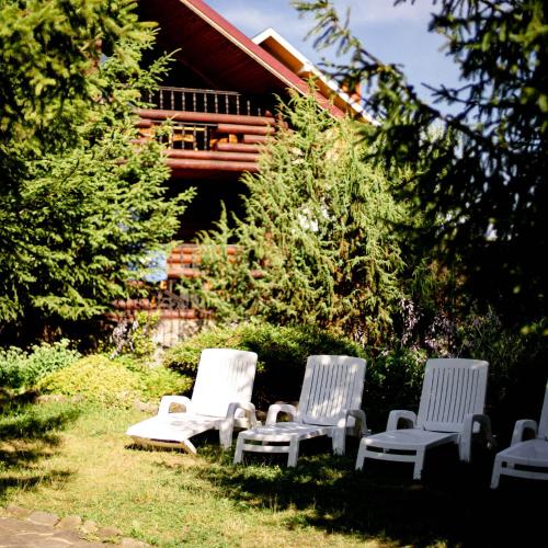four white chairs sitting in the grass in front of a house at ПАННА КАТЕРИНА in Solochin