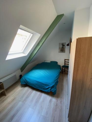 - une chambre mansardée avec un lit bleu dans l'établissement MAISONNETTE de charme avec cour privative Haute-Ville GRANVILLE, à Granville