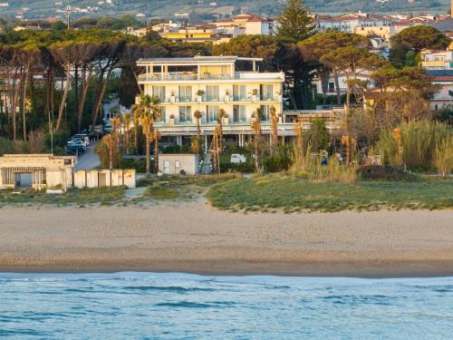 a large white house on a beach next to the water at Hotel Artemide Mare in Paestum