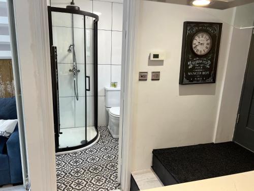 a bathroom with a shower and a clock on the wall at The End House at The Old Farmhouse in Cowbridge