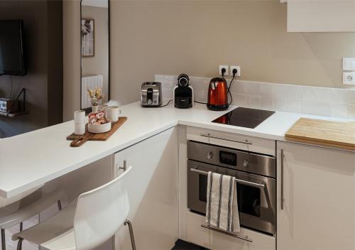 une cuisine blanche avec une cuisinière et un évier dans l'établissement Studio Etoile Carnot au cœur de la vieille ville, à Annecy