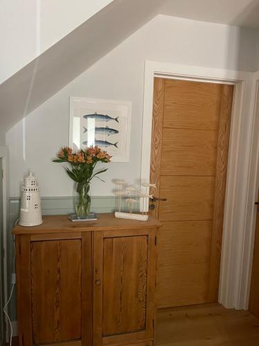 a vase of flowers on a wooden cabinet next to a door at Godden Green B & B Guesthouse in Newchurch