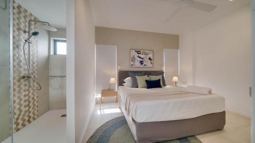 a white bedroom with a bed and a shower at Appart de Standing, Plage à 200m à Pieds in Grand Baie