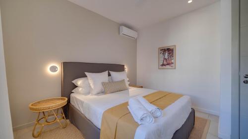 a bedroom with a bed with white sheets and a table at Appart de Standing, Plage à 200m à Pieds in Grand Baie