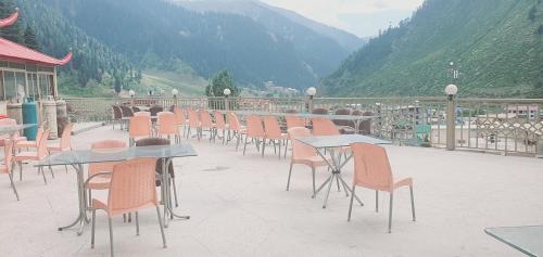 a row of tables and chairs on a patio with mountains at New Hilton Hotel in Naran