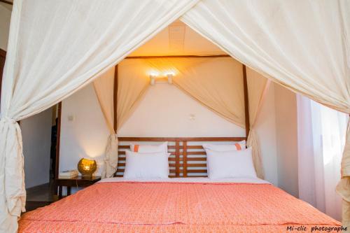 1 dormitorio con cama con dosel y cortinas blancas en MANGA BLUE'S GUEST HOUSE, en Fianarantsoa