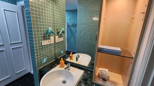 a blue tiled bathroom with a sink and a shower at Holiday Place Kuala Lumpur in Kuala Lumpur