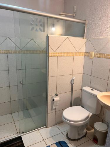 une salle de bain avec toilettes et douche en verre dans l'établissement Casa Paracuru, à Paracuru