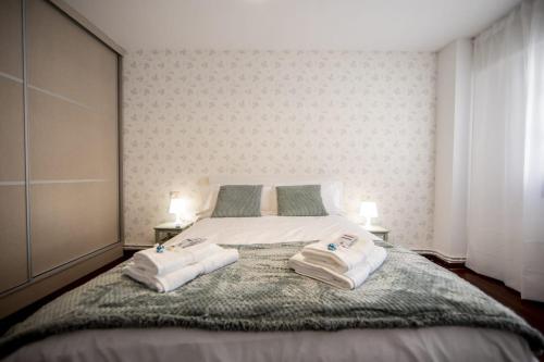 a bedroom with a bed with two towels on it at Dulces Estancias in Lalín
