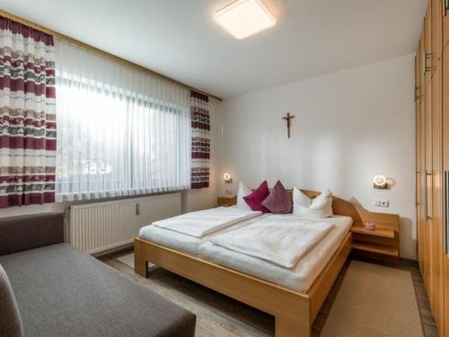 1 dormitorio con 1 cama y 1 cruz en la pared en Chiemgau Comfort C3 Ferienwohnanlage Oberaudorf mit Hallenbad und Sauna, en Oberaudorf