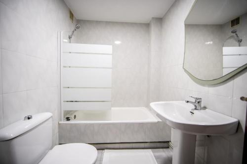 a white bathroom with a toilet and a sink at Dulces Estancias in Lalín