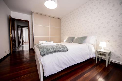 a bedroom with a large white bed and a side table at Dulces Estancias in Lalín