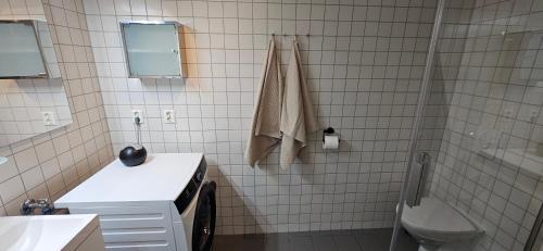 a white tiled bathroom with a sink and a toilet at Kirkenes Interlake in Kirkenes