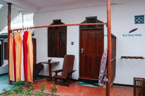 a room with two wooden doors and a chair at Surfers Park Arugambay in Arugam Bay