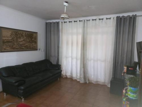 uma sala de estar com um sofá preto e cortinas brancas em SOBRADO Zona Sul Ribeirao Preto em Ribeirão Preto