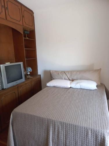 uma cama com duas almofadas e uma televisão num quarto em SOBRADO Zona Sul Ribeirao Preto em Ribeirão Preto
