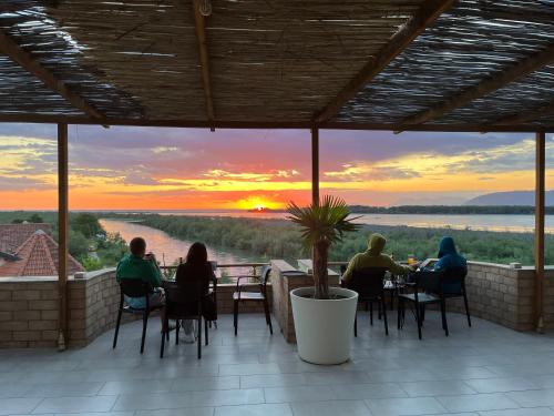 um grupo de pessoas sentadas às mesas a ver o pôr-do-sol em PARADISE Laguna Vain em Lezhë