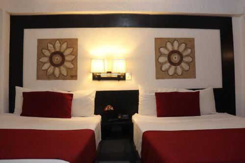 a hotel room with two beds with red pillows at Choco's Hotel in Villahermosa
