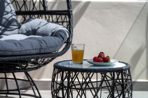 a glass of juice and a plate of strawberries on a table at V&V Boutique Villa in Argostoli