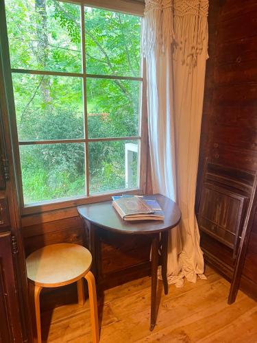 a table with a book on it next to a window at Cabane dans les bois in Sumène