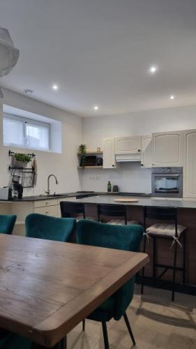 une cuisine avec une table en bois et des chaises vertes dans l'établissement Appartement neuf avec garage + fibre, à Blanzac
