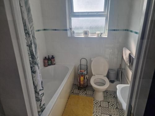 baño con bañera, aseo y ventana en Stunning 2-Bed House in Ferryside, en Ferryside