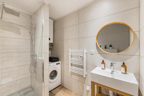 une salle de bain avec un lavabo et une machine à laver dans l'établissement CHILL HAVEN - Jacuzzi & Cinéma - Queen Size - Parking - Terrasse, à Saint-Étienne