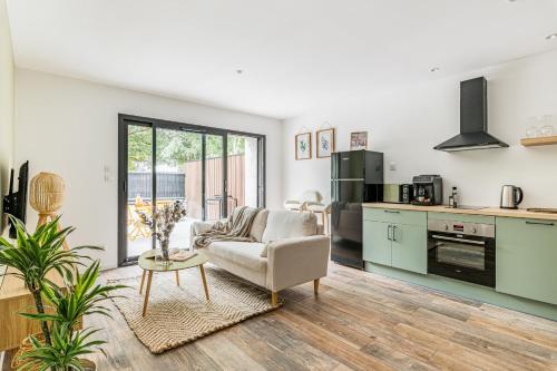 une cuisine et un salon avec un canapé et une table dans l'établissement CHILL HAVEN - Jacuzzi & Cinéma - Queen Size - Parking - Terrasse, à Saint-Étienne