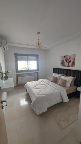 a white bedroom with a large bed and a window at Apparemment calm a Aouina in La Soukra