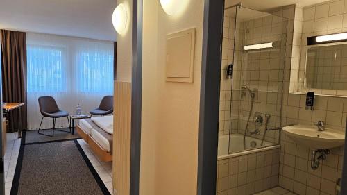 a room with a bathroom with a bed and a sink at Elha Hotel in Stuttgart