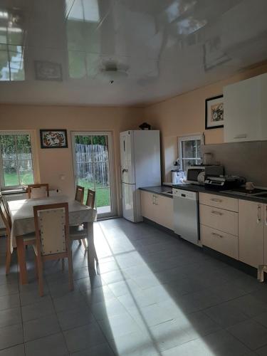 a kitchen with a table and a white refrigerator at Miško pasaka in Babrungėnai