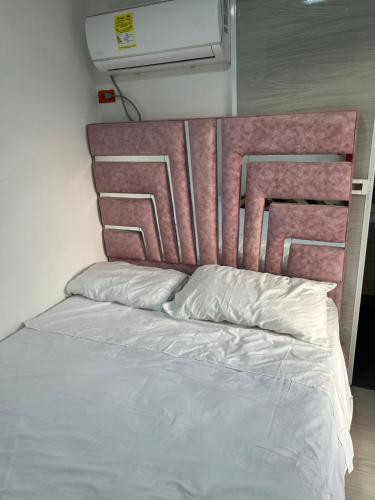 un lit avec une tête de lit rose dans une chambre dans l'établissement Habitaciones villa oti, à Ciénaga