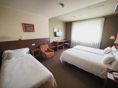 um quarto de hotel com duas camas e uma cadeira em Hotel EO em Ribadeo