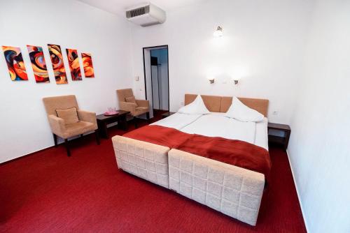 a bedroom with a large bed and two chairs at Hotel TISA in Băile Olăneşti