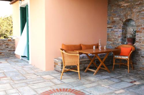 una mesa de madera y sillas en un patio en Vereniki Andros guesthouse, en Batsi
