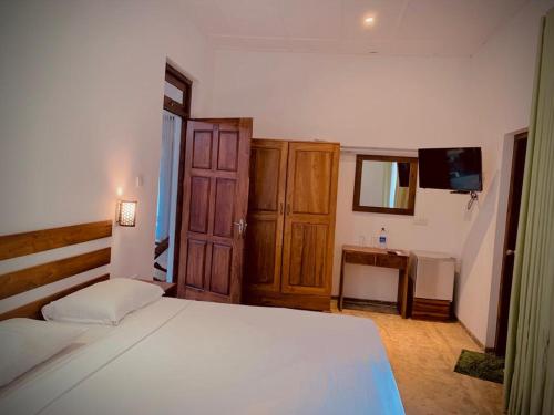 um quarto com uma grande cama branca e uma secretária em Raddagoda walawwa Hottel em Kurunegala