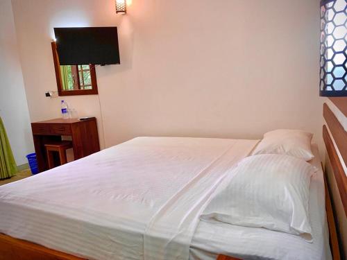 ein Bett mit weißer Bettwäsche und Kissen in einem Schlafzimmer in der Unterkunft Raddagoda walawwa Hottel in Kurunegala