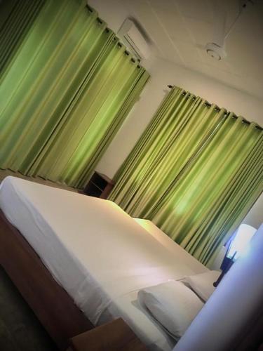 - une chambre avec un grand lit et des rideaux verts dans l'établissement Raddagoda walawwa Hottel, à Kurunegala