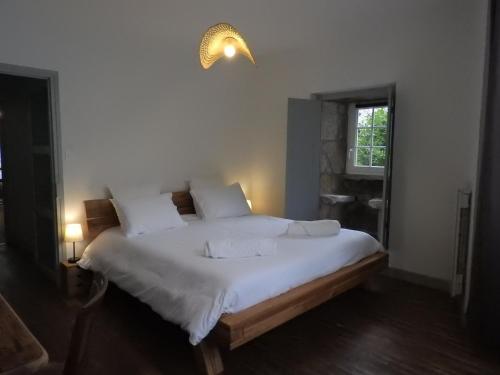 een slaapkamer met een bed met witte lakens en een raam bij Logis La P'tite Futée in Meymac