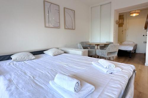- un grand lit blanc avec des serviettes dans l'établissement AUTRICHIENS - Haut de gamme Lumineux Central Jardin Parking, à Antibes