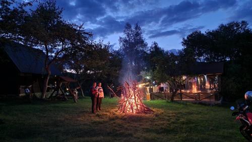 a man standing next to a fire pit at night at Sătucul de Vacanță Brăduleț in Uleni